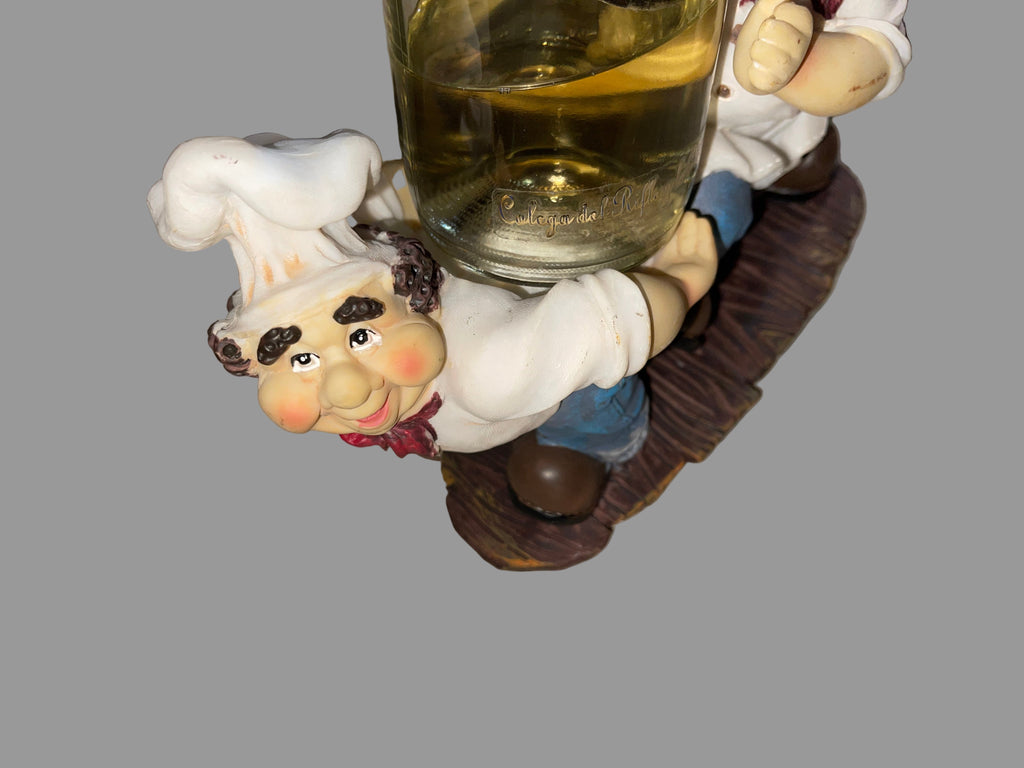 Decorative figurine of a chef holding a glass of wine on a striped surface
